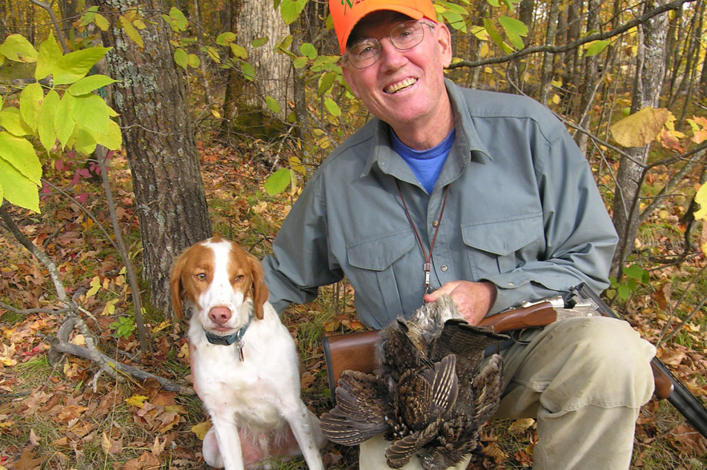 Hunter holding grouse with dog
